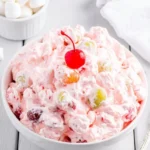 Colorful fruit salad topped with Cool Whip in a serving bowl.