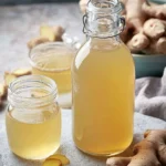 Homemade Ginger Simple Syrup in a glass bottle with fresh ginger root