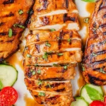 Grilled balsamic chicken served on a plate with fresh herbs and vegetables.