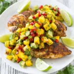 Grilled chicken topped with mango avocado salsa served on a plate