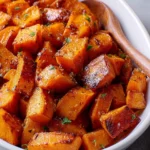 Bowl of maple roasted sweet potatoes garnished with herbs