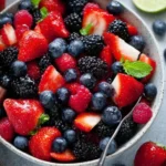 A vibrant mixed berry fruit salad featuring strawberries, blueberries, and raspberries.