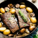 Delicious steak and potatoes dish served on a plate with fresh herbs.