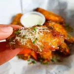 Baked garlic parmesan chicken wings on a platter garnished with herbs