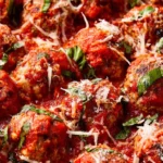 Plate of freshly baked meatballs with marinara sauce and herbs