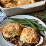 Homemade beef cobbler with tender meat and flaky topping in a baking dish