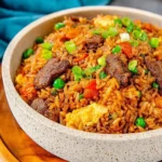 Delicious beef fried rice served in a bowl, garnished with vegetables.