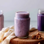 Blueberry Banana Protein Smoothie in a glass topped with fresh blueberries