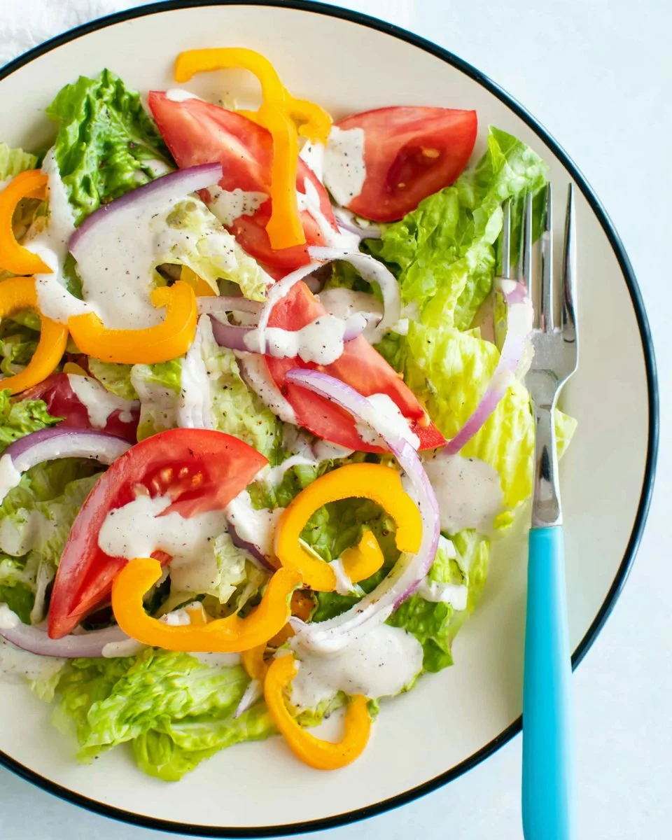 Homemade cashew ranch dressing in a bowl with fresh herbs and vegetables.