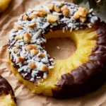 Chocolate covered pineapple rings on a white plate with fresh fruit garnishes.