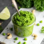 Creamy cashew pea pesto in a bowl with fresh peas and basil leaves