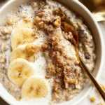 Bowl of creamy cinnamon overnight oats topped with fresh fruit and nuts