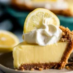 Slice of creamy lemon pie topped with whipped cream and lemon zest