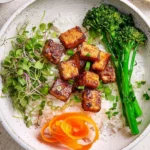 Plate of crispy marinated tofu garnished with herbs and served with vegetables