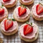 Frosted strawberry cookies decorated with pink icing on a white plate
