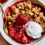 Healthy strawberry crumble served in a bowl with fresh strawberries on top.