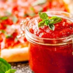 A bowl of homemade pizza sauce with fresh herbs and tomatoes