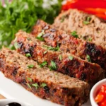 Mediterranean Meatloaf garnished with herbs and tomatoes on a white plate