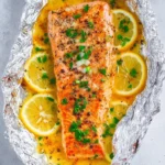 Delicious sheet pan honey lemon salmon with fresh herbs and lemon slices.