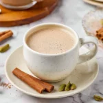 A steaming cup of spiced chai with aromatic spices and herbs.