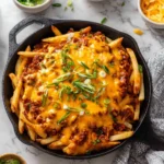 Plate of Vegan Chili Cheese Fries topped with vegan cheese and chili