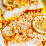 Baked Lemon Garlic Tilapia served on a plate with lemon slices and herbs.