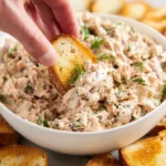 Canned salmon salad served in a bowl with fresh vegetables and herbs