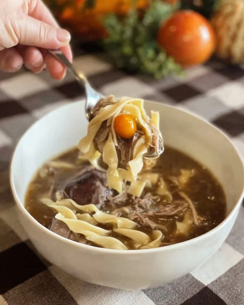 Crock Pot Beef and Noodles served in a bowl, garnished with fresh herbs.