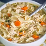 Crockpot chicken noodle soup in a bowl with vegetables and herbs