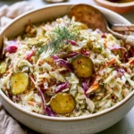 Bowl of dill pickle coleslaw with crunchy cabbage and pickle slices