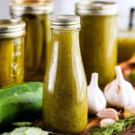 Bottle of dill pickle hot sauce with fresh dill and pickles