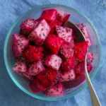 Colorful bowl of Dragon Fruit Salsa with ingredients on a wooden table