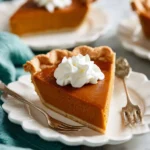 Easy pumpkin pie served on a plate with whipped cream and a sprinkle of cinnamon