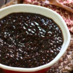 A spoonful of fermented black bean sauce in a bowl, showcasing its rich texture and dark color.