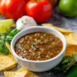 Grilled tomato salsa served in a bowl with fresh cilantro and lime
