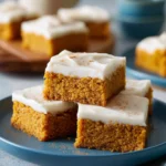 Delicious homemade pumpkin bars topped with cream cheese frosting on a plate
