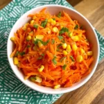 Shredded carrot salad with fresh herbs and dressing in a bowl
