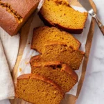 Simple homemade pumpkin bread fresh out of the oven, garnished with spices.