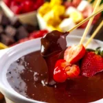 Creamy slow cooker chocolate fondue served with fruits and treats.