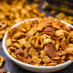 A bowl of smoked Chex Mix with savory snacks and spices.