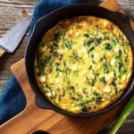 Spinach and feta frittata served on a plate, garnished with herbs.