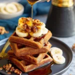 Delicious vegan banana waffles served with fresh fruit and maple syrup.