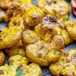 Crispy smashed potatoes served with herbs and spices on a plate