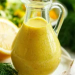 Homemade Lemon Dill Dressing in a glass jar with fresh herbs and lemons.